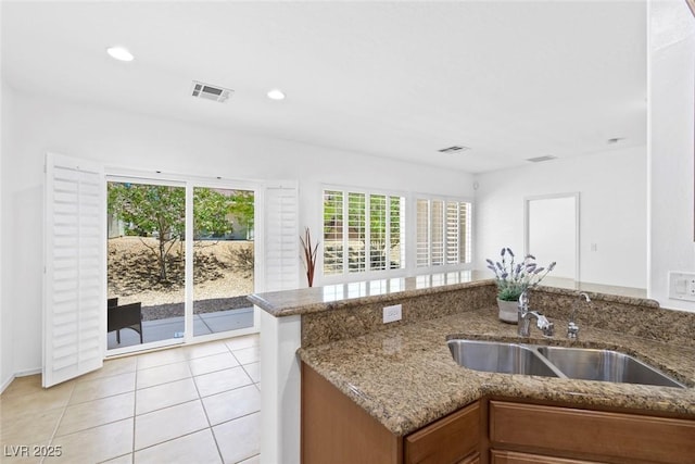 7448 Lintwhite St, North Las Vegas, NV 89084 - kitchen featuring a sink, brown cabinetry, stone counters, recessed lighting, and light tile patterned flooring