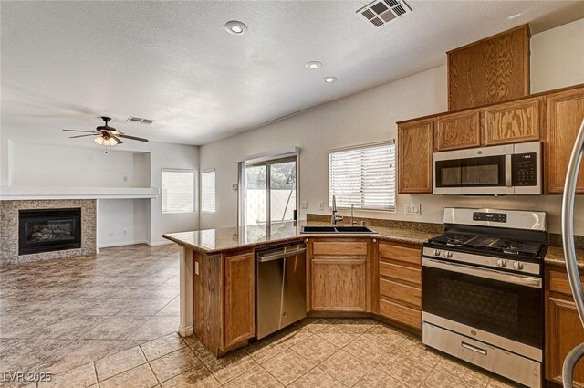 74 Harbor Coast St, Las Vegas, NV 89148 - kitchen with stainless steel appliances, a sink, a ceiling fan, dark countertops, and brown cabinetry