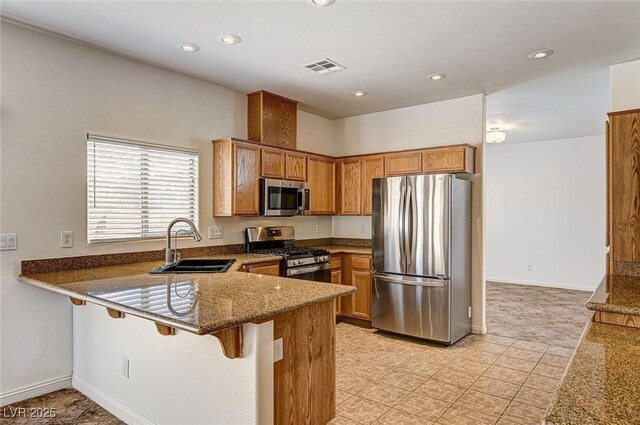74 Harbor Coast St, Las Vegas, NV 89148 - kitchen with stainless steel appliances, a sink, a peninsula, brown cabinets, and recessed lighting