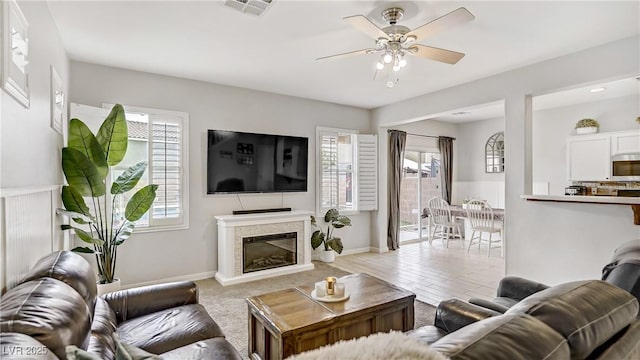 482 Painted Sage Ct, Henderson, NV 89015 - living area with a glass covered fireplace, ceiling fan, and baseboards