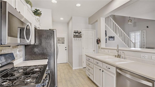 482 Painted Sage Ct, Henderson, NV 89015 - kitchen featuring stainless steel appliances, a sink, white cabinetry, light countertops, and backsplash