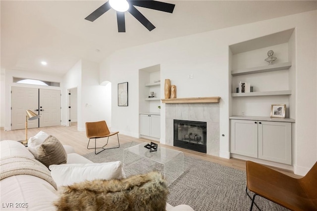 4016 Tyler William Ln, Las Vegas, NV 89130 - living room with built in shelves, a ceiling fan, light wood-style floors, lofted ceiling, and a tiled fireplace