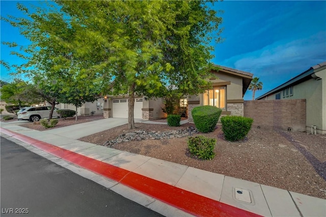 8128 Devils Canyon St, North Las Vegas, NV 89085 - view of property hidden behind natural elements with driveway, stucco siding, stone siding, and an attached garage