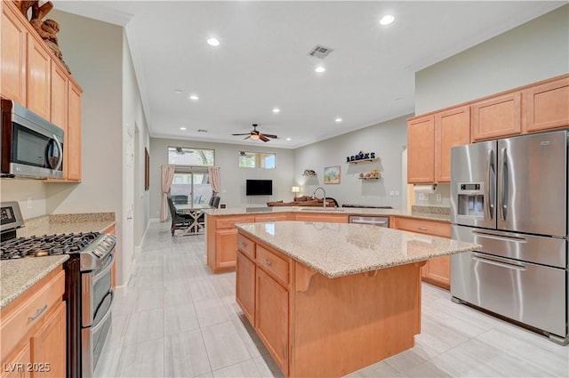 8128 Devils Canyon St, North Las Vegas, NV 89085 - kitchen with stainless steel appliances, a peninsula, light brown cabinets, a ceiling fan, and a kitchen island