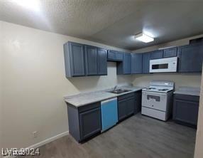304 Orland St Unit 39, Las Vegas, NV 89107 - kitchen with white appliances, wood finished floors, a sink, light countertops, and baseboards
