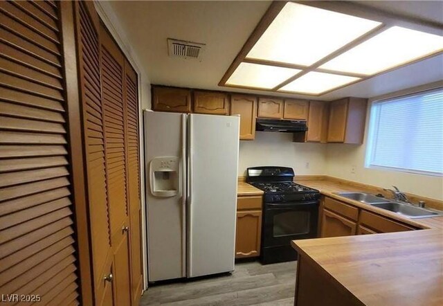 854 Stainglass Ln, Las Vegas, NV 89110 - kitchen with white fridge with ice dispenser, gas stove, a sink, under cabinet range hood, and light wood finished floors