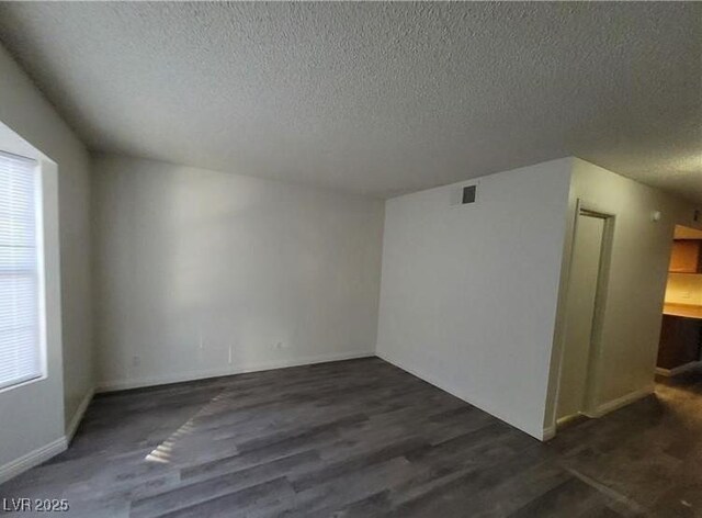 854 Stainglass Ln, Las Vegas, NV 89110 - unfurnished room with a textured ceiling, plenty of natural light, baseboards, and wood finished floors