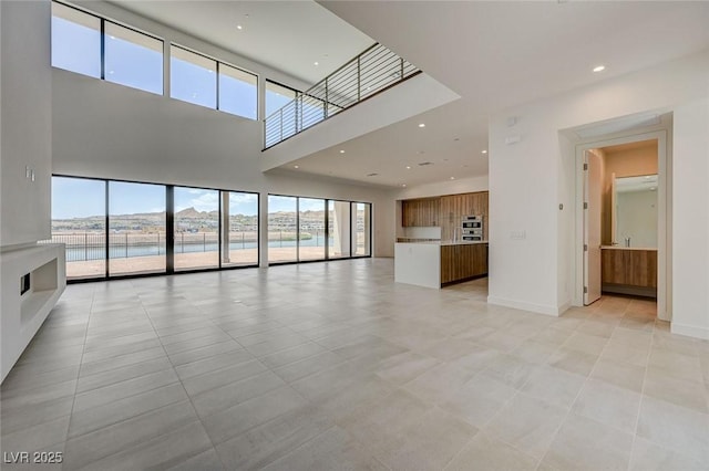 1600 Pleasant Bay Ct, Henderson, NV 89011 - unfurnished living room featuring a towering ceiling, healthy amount of natural light, light tile patterned floors, recessed lighting, and baseboards