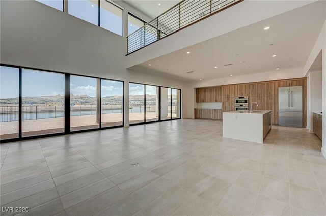 1600 Pleasant Bay Ct, Henderson, NV 89011 - unfurnished living room with a sink, a towering ceiling, a water view, and light tile patterned floors