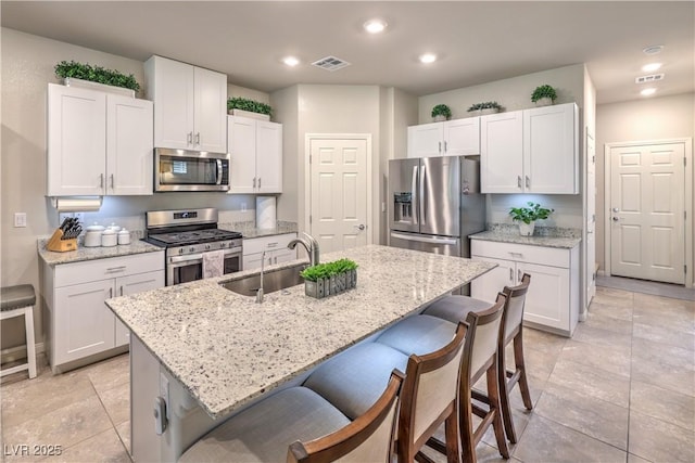 9229 Brayden Bay St, Las Vegas, NV 89178 - kitchen with stainless steel appliances, a sink, a breakfast bar, white cabinets, and recessed lighting