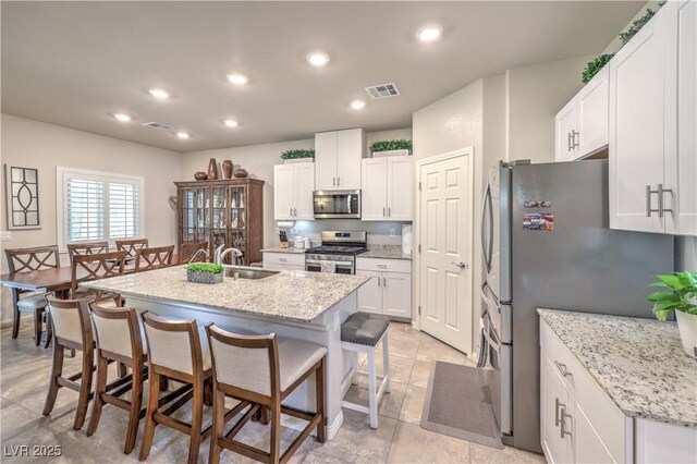 9229 Brayden Bay St, Las Vegas, NV 89178 - kitchen featuring stainless steel appliances, a sink, a kitchen breakfast bar, an island with sink, and white cabinetry