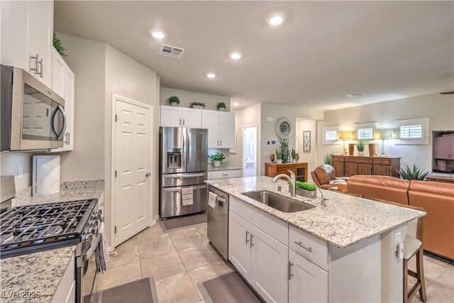 9229 Brayden Bay St, Las Vegas, NV 89178 - kitchen featuring appliances with stainless steel finishes, a sink, white cabinets, a center island with sink, and open floor plan