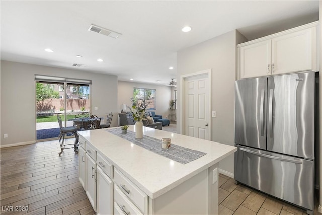 6783 Pleasant Flower St, Las Vegas, NV 89149 - kitchen featuring freestanding refrigerator, wood finish floors, baseboards, a center island, and white cabinets