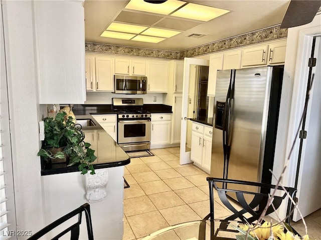 2820 Bluff Point Dr, Las Vegas, NV 89134 - kitchen with appliances with stainless steel finishes, dark countertops, white cabinetry, and light tile patterned flooring