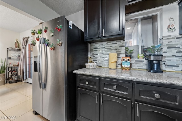 1916 Canosa Ave, Las Vegas, NV 89104 - kitchen with stainless steel refrigerator with ice dispenser, a textured ceiling, backsplash, light tile patterned floors, and dark cabinets
