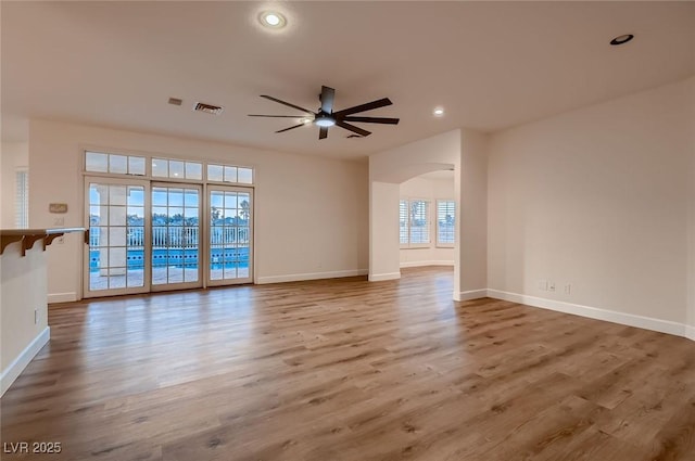 2448 Ram Crossing Way, Henderson, NV 89074 - unfurnished living room with arched walkways, ceiling fan, wood finished floors, baseboards, and recessed lighting