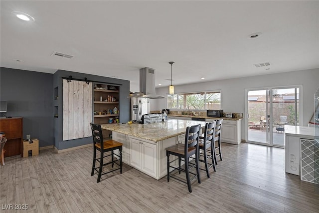 603 Palmhurst Dr, Las Vegas, NV 89145 - kitchen featuring island range hood, a kitchen breakfast bar, light wood finished floors, light stone countertops, and recessed lighting