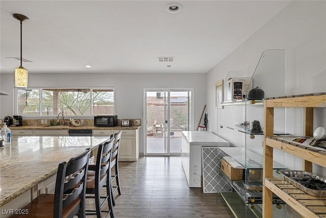 603 Palmhurst Dr, Las Vegas, NV 89145 - kitchen featuring light stone countertops, dark wood-style floors, a sink, recessed lighting, and a breakfast bar