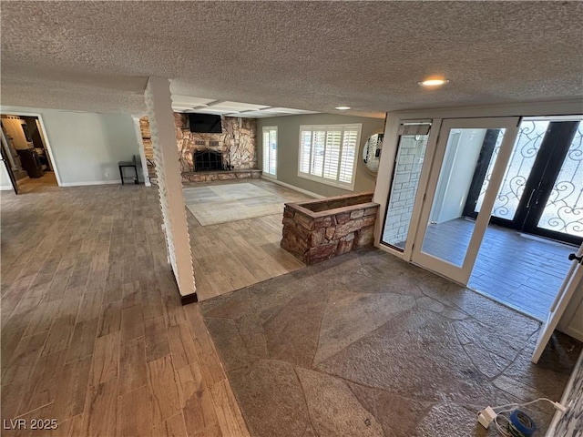 1819 Beverly Way, Las Vegas, NV 89104 - unfurnished living room with wood finished floors, a textured ceiling, a stone fireplace, and baseboards
