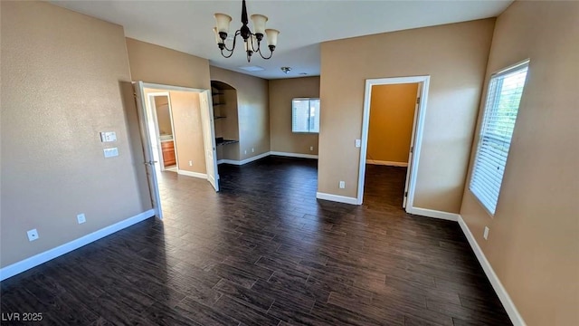 8159 Base Camp Ave, Las Vegas, NV 89178 - empty room with a chandelier, plenty of natural light, arched walkways, and dark wood-type flooring