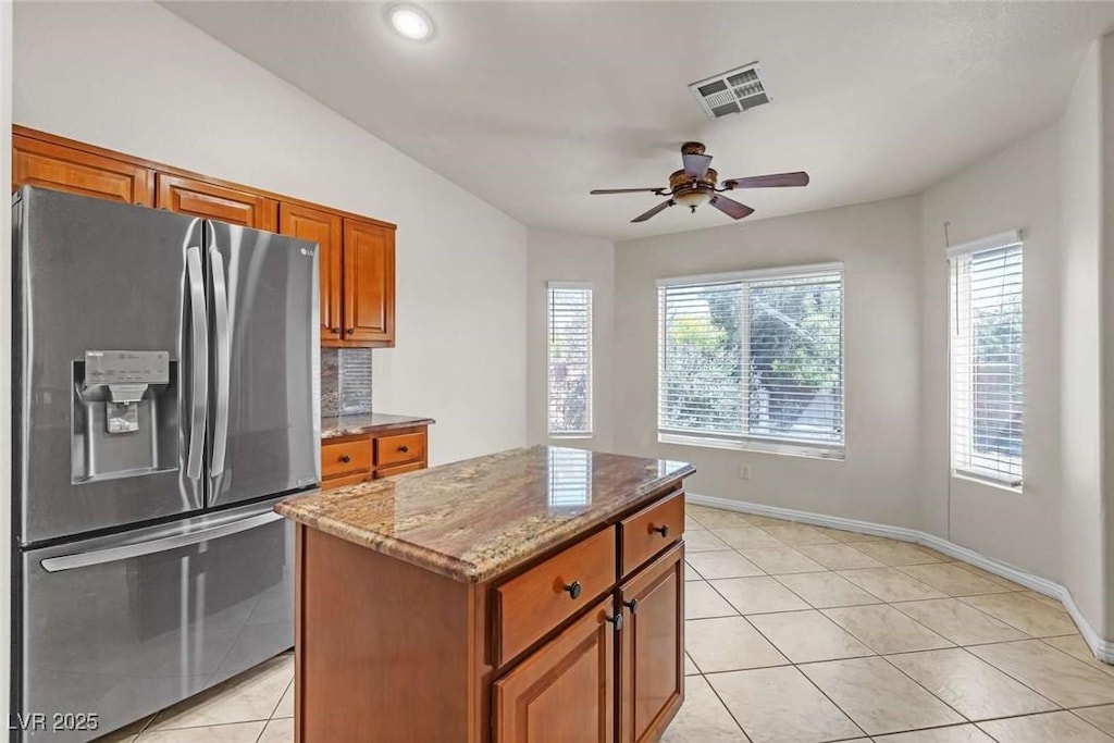 3521 Amish Ave, North Las Vegas, NV 89031 - kitchen featuring stainless steel refrigerator with ice dispenser, healthy amount of natural light, brown cabinets, light stone countertops, and recessed lighting
