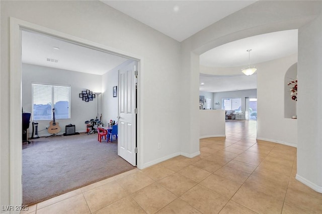 2613 Velodrome Ct, Henderson, NV 89044 - hallway featuring arched walkways, light tile patterned floors, baseboards, and light carpet