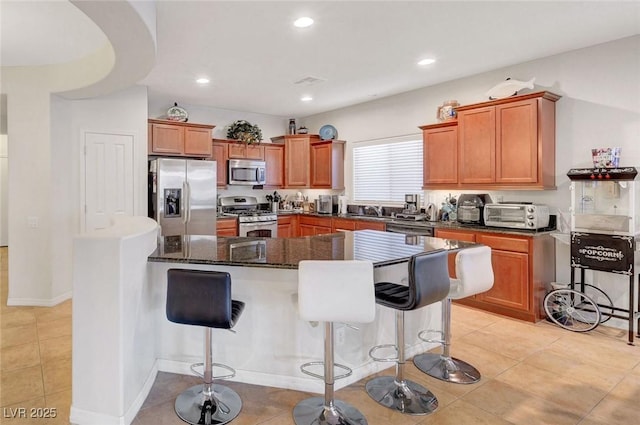 2613 Velodrome Ct, Henderson, NV 89044 - kitchen featuring appliances with stainless steel finishes, a kitchen breakfast bar, a kitchen island, brown cabinets, and recessed lighting