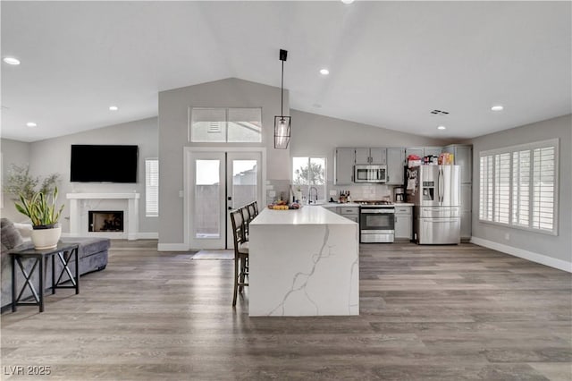 2711 Briarcliff Ave, Henderson, NV 89074 - kitchen featuring appliances with stainless steel finishes, lofted ceiling, gray cabinetry, baseboards, and open floor plan