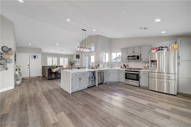 2711 Briarcliff Ave, Henderson, NV 89074 - kitchen featuring appliances with stainless steel finishes, lofted ceiling, beverage cooler, a peninsula, and light countertops