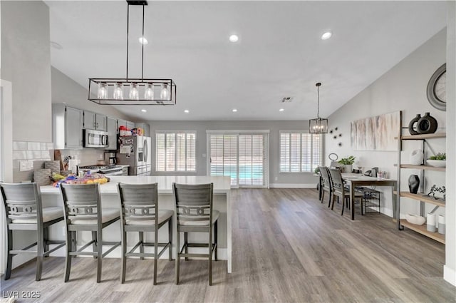 2711 Briarcliff Ave, Henderson, NV 89074 - kitchen with appliances with stainless steel finishes, a peninsula, light wood finished floors, light countertops, and a chandelier
