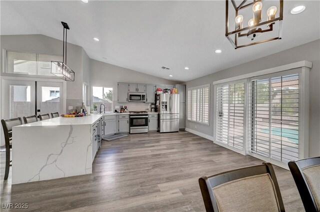 2711 Briarcliff Ave, Henderson, NV 89074 - kitchen with appliances with stainless steel finishes, lofted ceiling, a sink, a chandelier, and light wood finished floors