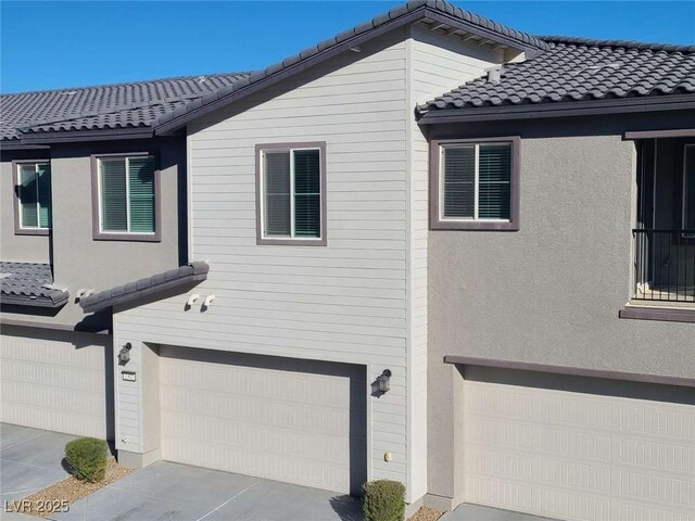 7332 N Decatur Blvd Unit 2, North Las Vegas, NV 89084 - view of property exterior featuring an attached garage, a tile roof, and stucco siding