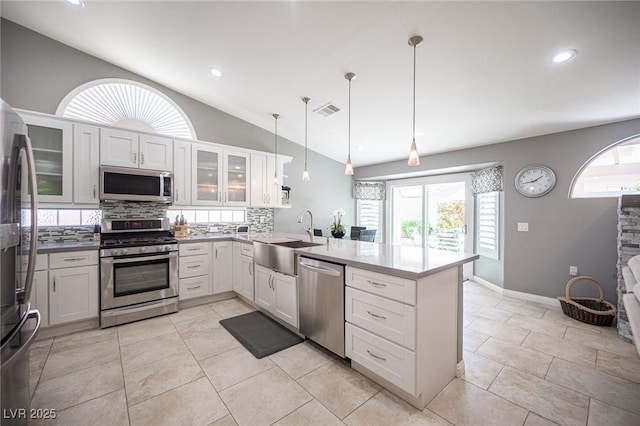 6417 Fisher Ave, Las Vegas, NV 89130 - kitchen featuring stainless steel appliances, a sink, a peninsula, lofted ceiling, and backsplash