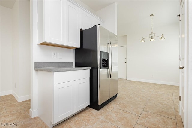 3041 Gary Cooper St Unit 103, Las Vegas, NV 89122 - kitchen with stainless steel fridge, white cabinetry, baseboards, decorative light fixtures, and light tile patterned floors