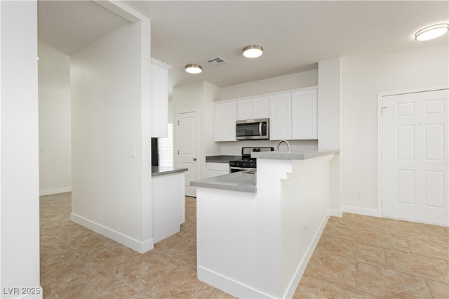 3041 Gary Cooper St Unit 103, Las Vegas, NV 89122 - kitchen with stainless steel appliances, white cabinetry, a peninsula, and baseboards