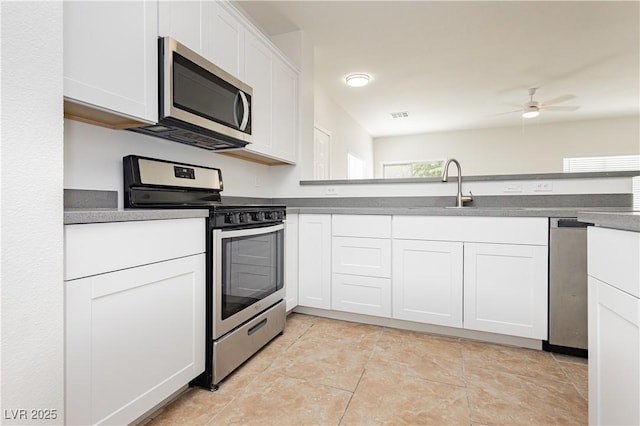 3041 Gary Cooper St Unit 103, Las Vegas, NV 89122 - kitchen featuring appliances with stainless steel finishes, a sink, white cabinets, a ceiling fan, and dark countertops