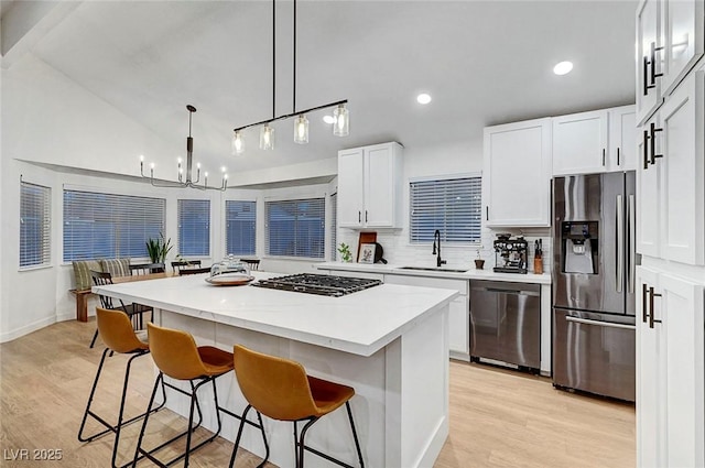 58 Pleasant Dale Dr, Henderson, NV 89074 - kitchen with stainless steel appliances, a sink, a kitchen bar, a center island, and light wood-type flooring