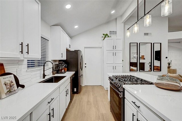 58 Pleasant Dale Dr, Henderson, NV 89074 - kitchen with a sink, black gas range oven, decorative backsplash, white cabinets, and light wood-style floors