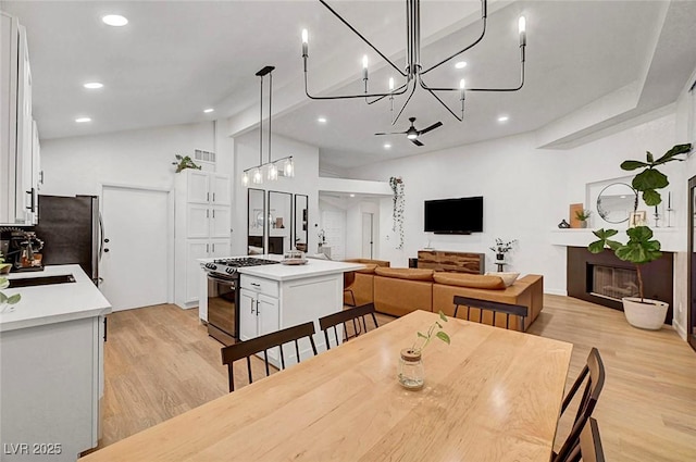 58 Pleasant Dale Dr, Henderson, NV 89074 - dining space featuring light wood-style flooring, a chandelier, recessed lighting, a glass covered fireplace, and lofted ceiling