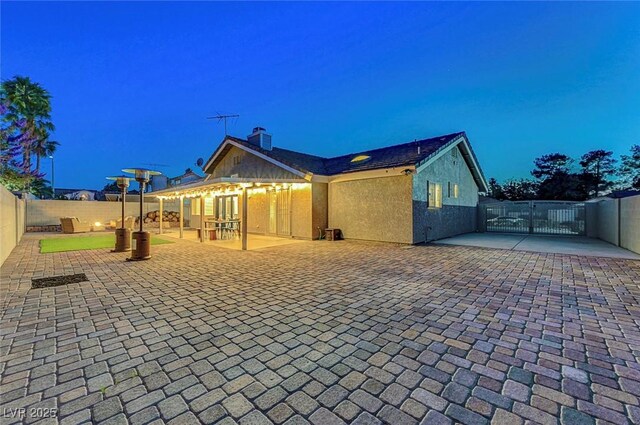 58 Pleasant Dale Dr, Henderson, NV 89074 - back of property featuring a gate, a fenced backyard, a patio area, a chimney, and stucco siding