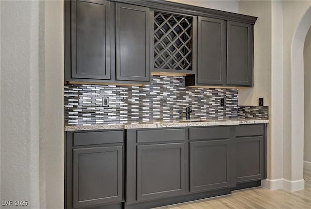 8544 Garden Valley Ct, Las Vegas, NV 89178 - indoor bar featuring backsplash, light wood-style floors, baseboards, and arched walkways