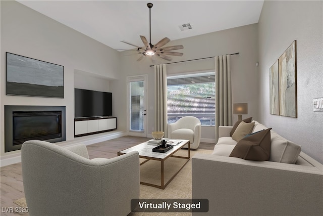 8544 Garden Valley Ct, Las Vegas, NV 89178 - living room featuring light wood-style floors, a ceiling fan, a glass covered fireplace, and baseboards