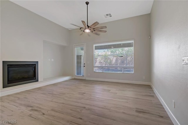 8544 Garden Valley Ct, Las Vegas, NV 89178 - unfurnished living room featuring light wood-type flooring, ceiling fan, a glass covered fireplace, and baseboards