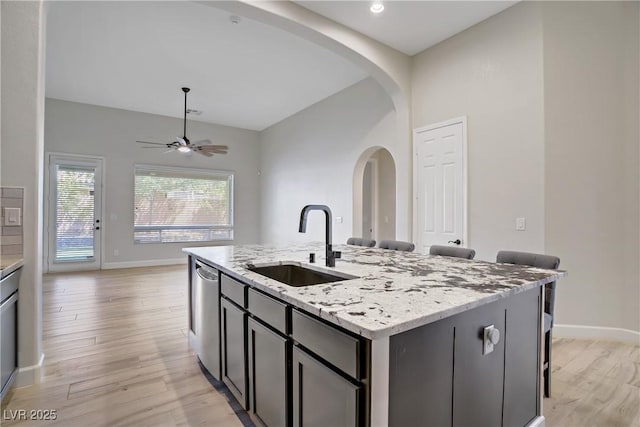8544 Garden Valley Ct, Las Vegas, NV 89178 - kitchen with stainless steel dishwasher, a sink, ceiling fan, arched walkways, and light wood-style floors