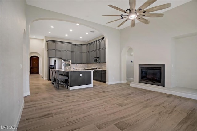 8544 Garden Valley Ct, Las Vegas, NV 89178 - kitchen featuring stainless steel appliances, gray cabinetry, open floor plan, a center island with sink, and a kitchen bar