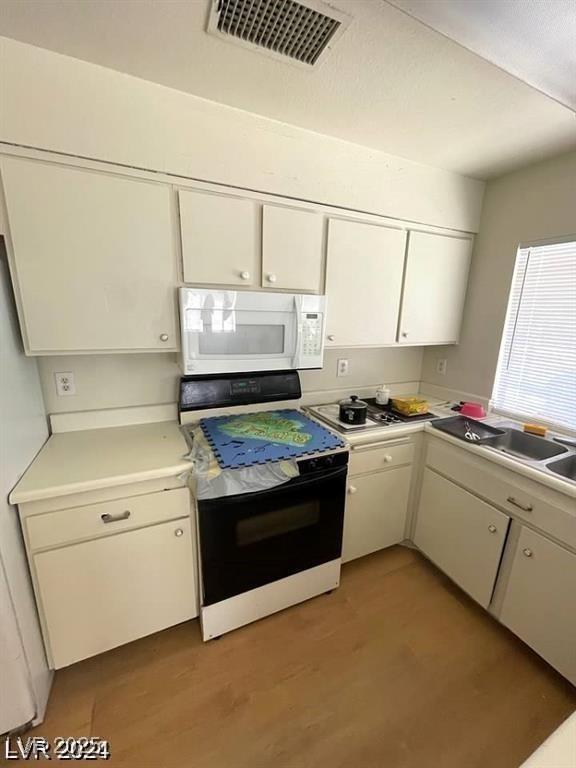 45 Logan Ct, Las Vegas, NV 89110 - kitchen with range with electric stovetop, white microwave, white cabinetry, and light countertops