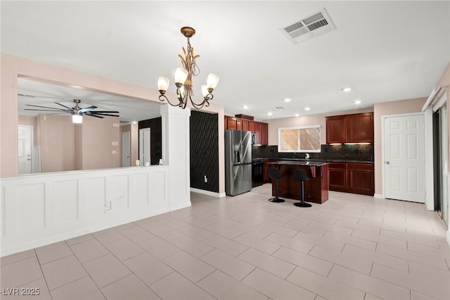 11755 Garland Grove Ln, Las Vegas, NV 89183 - kitchen with stainless steel fridge, a kitchen bar, decorative backsplash, dark countertops, and a chandelier