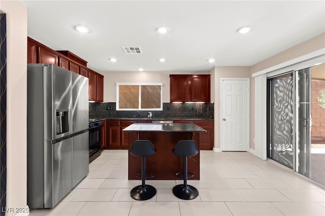 11755 Garland Grove Ln, Las Vegas, NV 89183 - kitchen featuring stainless steel fridge with ice dispenser, black gas range, reddish brown cabinets, a breakfast bar area, and recessed lighting