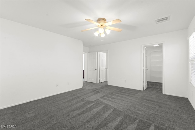 11755 Garland Grove Ln, Las Vegas, NV 89183 - unfurnished bedroom featuring dark carpet, a spacious closet, baseboards, and ceiling fan
