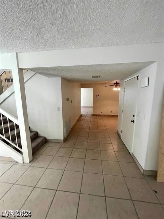5243 Sunnywood Dr, Las Vegas, NV 89120 - hall with a textured ceiling, light tile patterned flooring, baseboards, and stairs